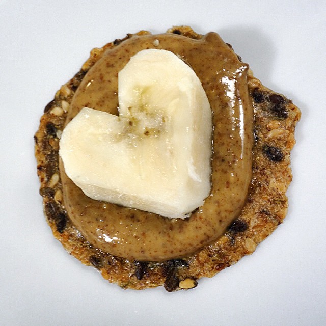banana shaped like a heart sits on a cracker with peanut butter spread on it
